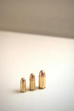 Three bullets of different calibers on a white surface. Stock Photos