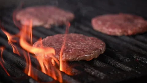 Three burgers are cooked on an open flame grill. Burgers are brown and sizzling. Vídeo Stock 284672117