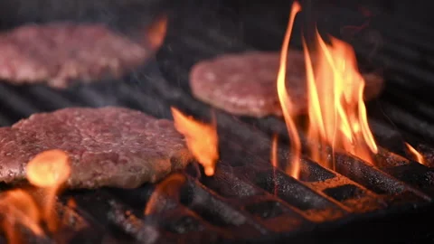 Three burgers are cooked on an open flame grill. Burgers are brown and sizzling. Vídeo Stock 284672286