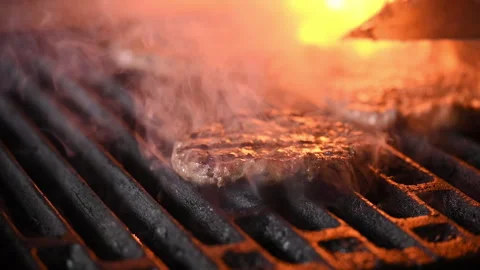 Three burgers are cooked on an open flame grill. Burgers are brown and sizzling. Vídeo Stock 284672855