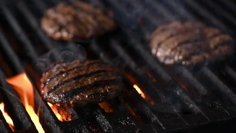 Three burgers are cooked on an open flame grill. Burgers are brown and sizzling. Vídeo Stock 284673141