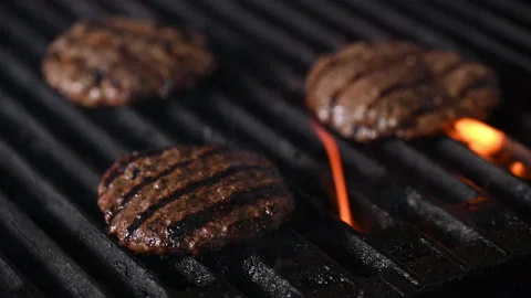 Three burgers are cooked on an open flame grill. Burgers are brown and sizzling. Vídeo Stock 284673203