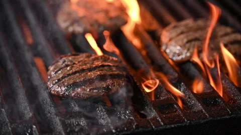 Three burgers are cooked on an open flame grill. Burgers are brown and sizzling. Vídeo Stock 284673353