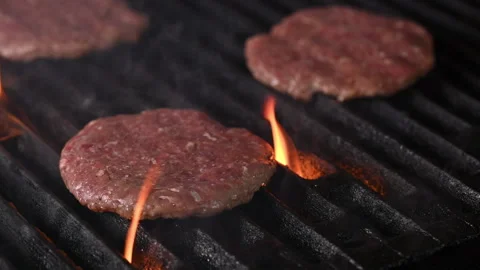 Three burgers are cooked on an open flame grill. Burgers are brown and sizzling. Vídeo Stock 284673722