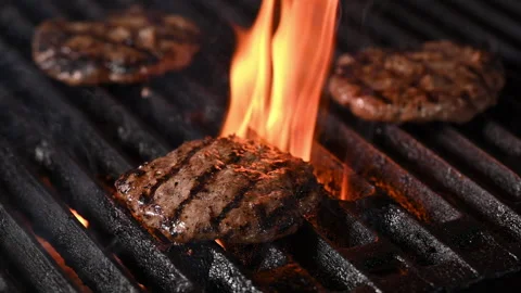 Three burgers are cooked on an open flame grill. Burgers are brown and sizzling. 動画素材 284674282