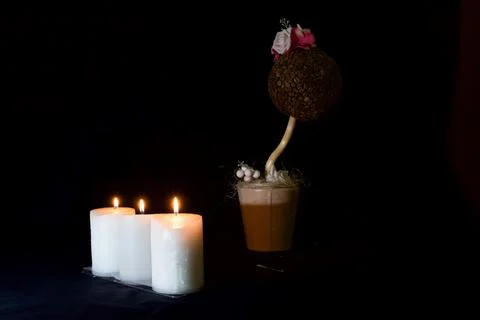 Three burning candles, an artificial flower made of coffee beans Stock Photos
