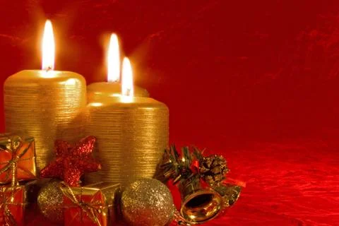 Three burning candles in a christmas setting with seasonal decorations. Stock Photos