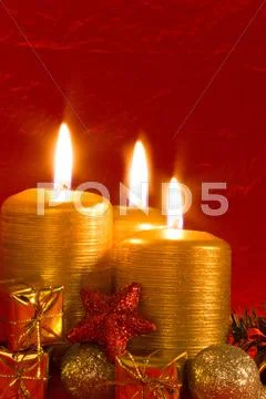 Three burning candles in a christmas setting with seasonal decorations. Stock Photos