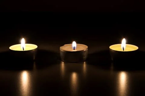 Three burning candles in the dark Stock Photos