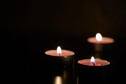 Three burning candles in the dark Stock Photos