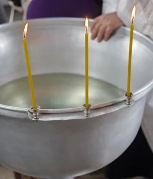 Three burning candles on the edge of the silver font before the Orthodox rite Foto stock