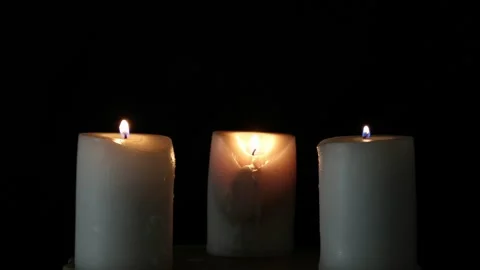 Three burning candles on the oak stand in the dark Stock Footage 306947222