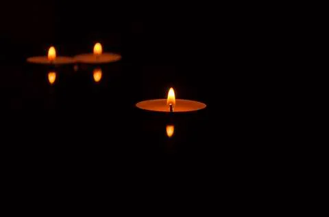 Three burning candles with reflection on black background Stock Photos