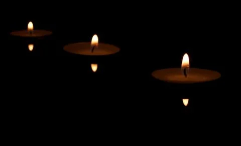 Three burning candles with reflection on black background Stock Photos