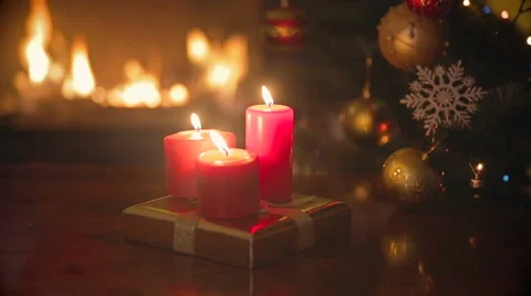 Three burning red Christmas candles on dinner table at living room next to fi Stock Footage