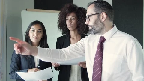 Three business partners holding documents and discussing project Stock Footage 137512905