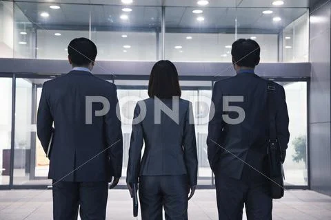Three business people standing in a row, rear view Stock Photos