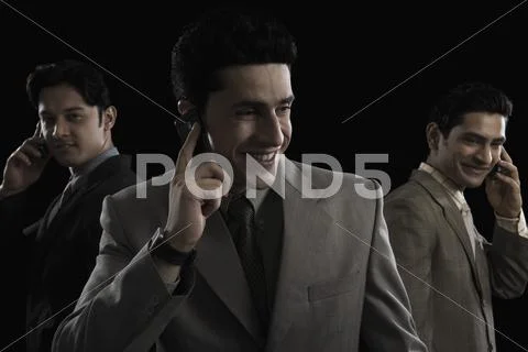 Three businessmen talking on mobile phones Stock Photos