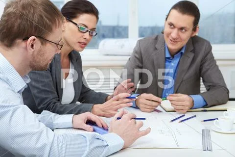 Three businesspeople sitting at table and making a draft Stock Photos