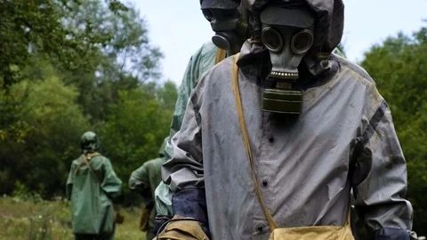 Three cadets of military men in a protective suit in a gas mask with a mine Stock Footage 116403213