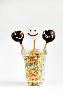Three cake pops with painted smiles isolated Stock Photos