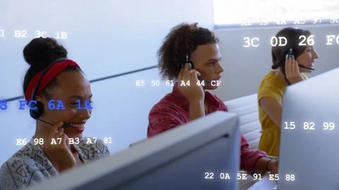 Three call-center agents taking incoming calls at desks on headsets while code Stock Footage 333720121