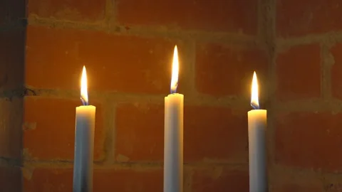Three candles are burning against the brick wall Stock Footage 136479654