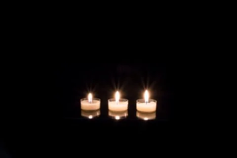 Three candles on black background Foto stock