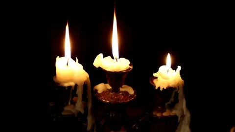Three candles burn in a candlestick on a black background. Video stock 116552473