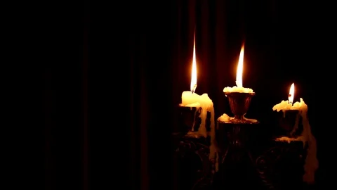 Three candles burn in a candlestick on a black background. Stock Footage 116554423