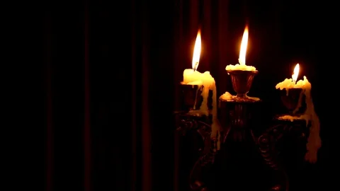 Three candles burn in a candlestick on a black background. Stock Footage 120105036