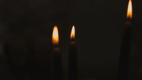 Three candles burning on a black background on the day of a religious festival Stock Footage 123800010