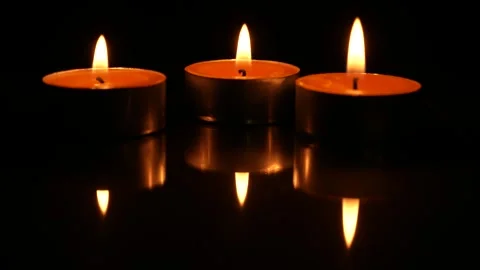 Three candles burning, isolated on black background Видео 267549391