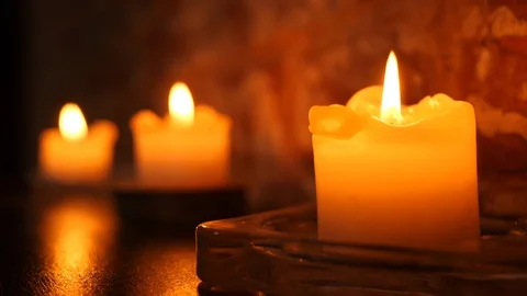 Three candles burning on a table making cozy warm light in interior Stock Footage 119014206