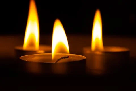 Three candles in the dark, close up Stock Photos