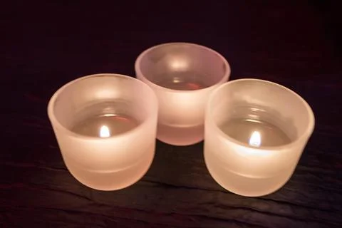Three candles placed on a table Stock Photos
