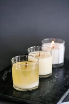 Three candles stand on the table on a gray background. Stock Photos