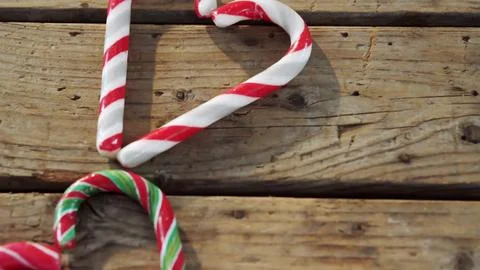 Three candy canes are resting on rustic wooden tabletop in flat design, with Foto stock