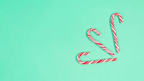 Three candy canes on a light green background. Minimal holiday frame. Copy sp Stock Photos