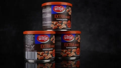 Three cans of Ultje extra roasted peanuts stacked on a reflective black surface Stock Footage 310067613