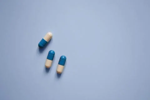 Three capsules on a blue background, medication, medical workers day, medic.. Stock Photos