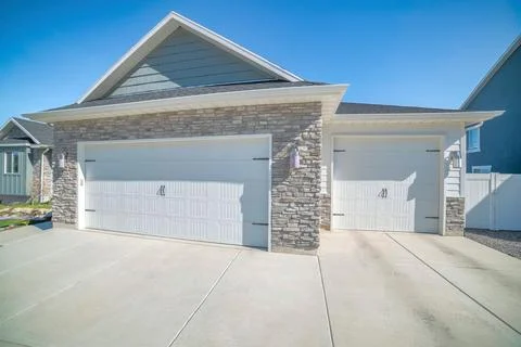 Three-car side hinged garage doors with stone veneer wall siding Foto stock
