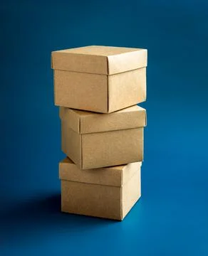 Three cardboard parcel boxes stack on blue background, vertical style. Carton Foto stock