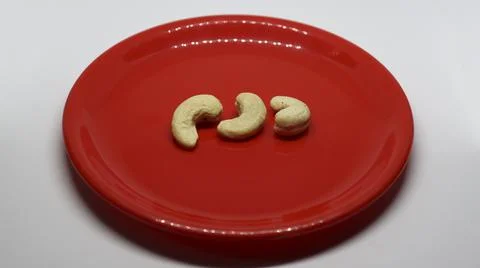 Three cashew nuts is on a white background on a red plate Foto stock