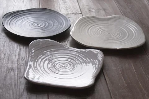Three ceramic plates with spiral texture on rustic wooden table minimal Stock Photos
