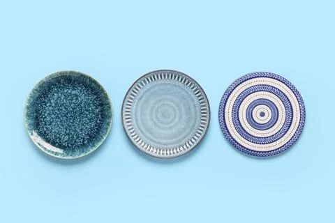 Three ceramic plates with unique textures and patterns on a light blue backgr Photos