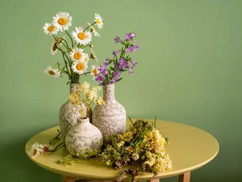 Three ceramic vases with wildflowers on a table. Foto stock