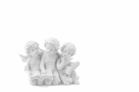 Three ceramic white angels read the book, dreaming and thinking. Isolated o.. Stock Photos