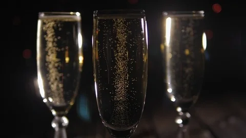 Three champagne glasses on a black background with multi-colored flashing lights Stock Footage 123988188