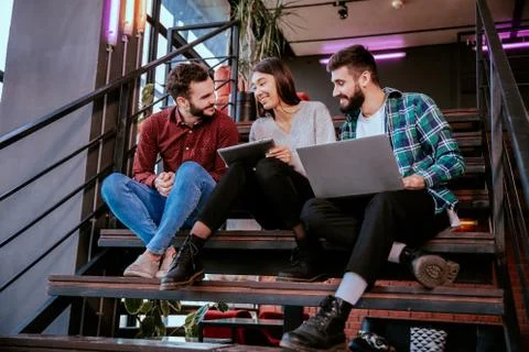 Three charismatic young office workers working hard using tablet and notebook to Stock Photos